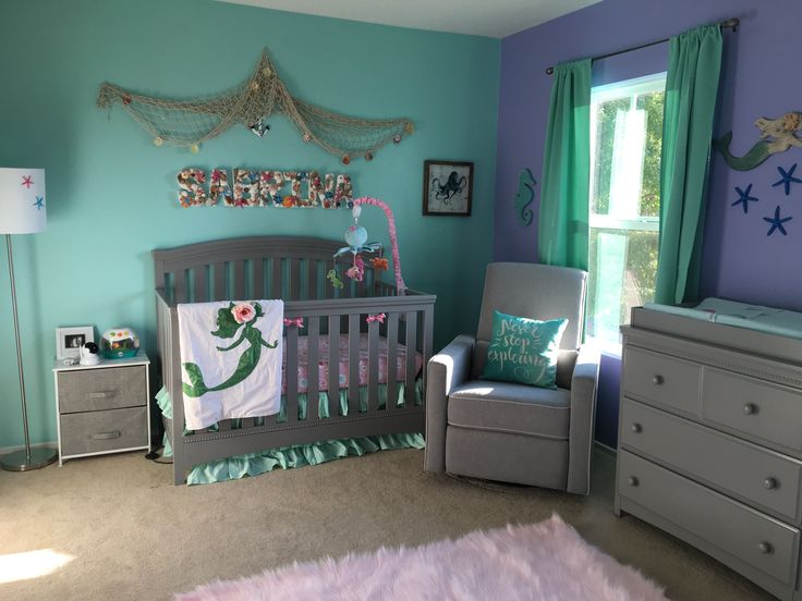 a baby's room decorated in blue and green with mermaid themed decor on the walls