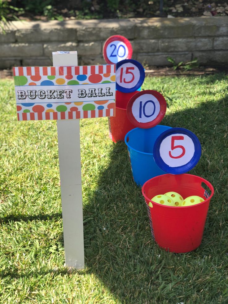 buckets filled with apples sitting in the grass near a sign that says bucket ball