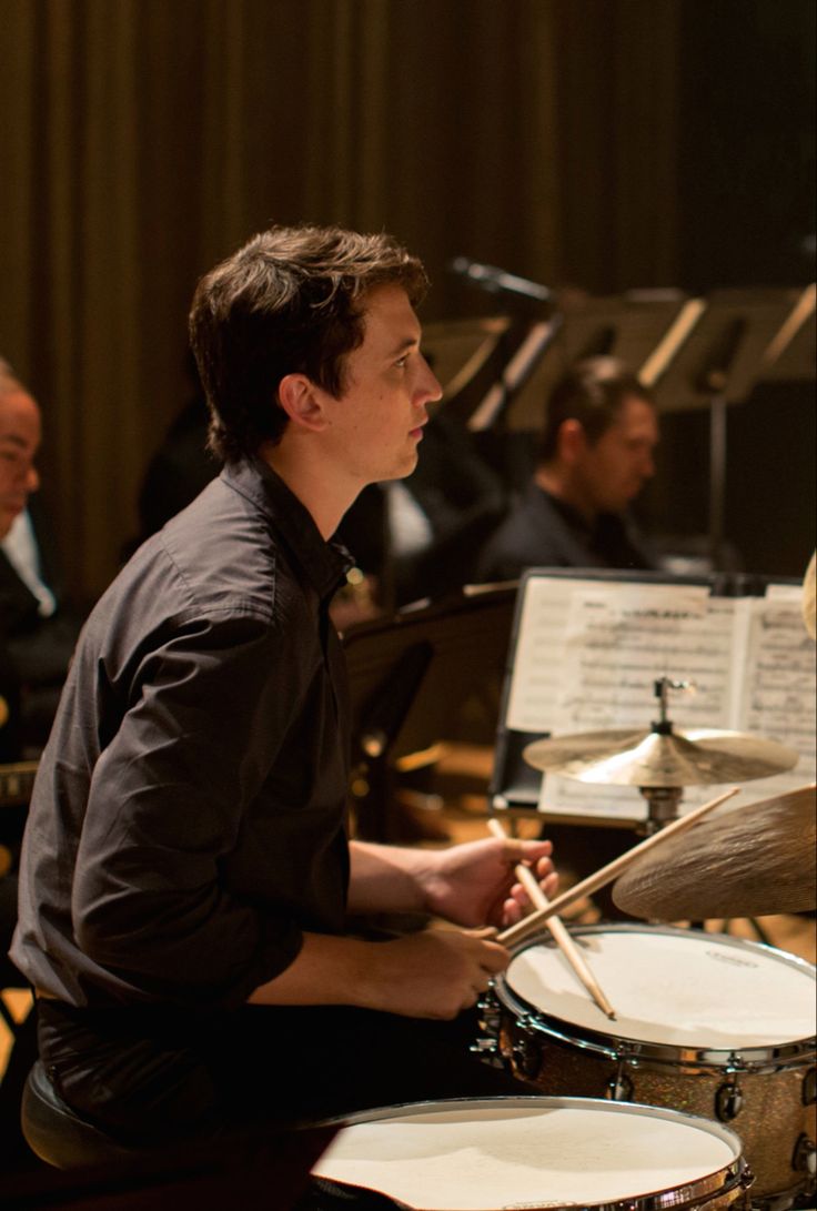 a man sitting in front of a drum set