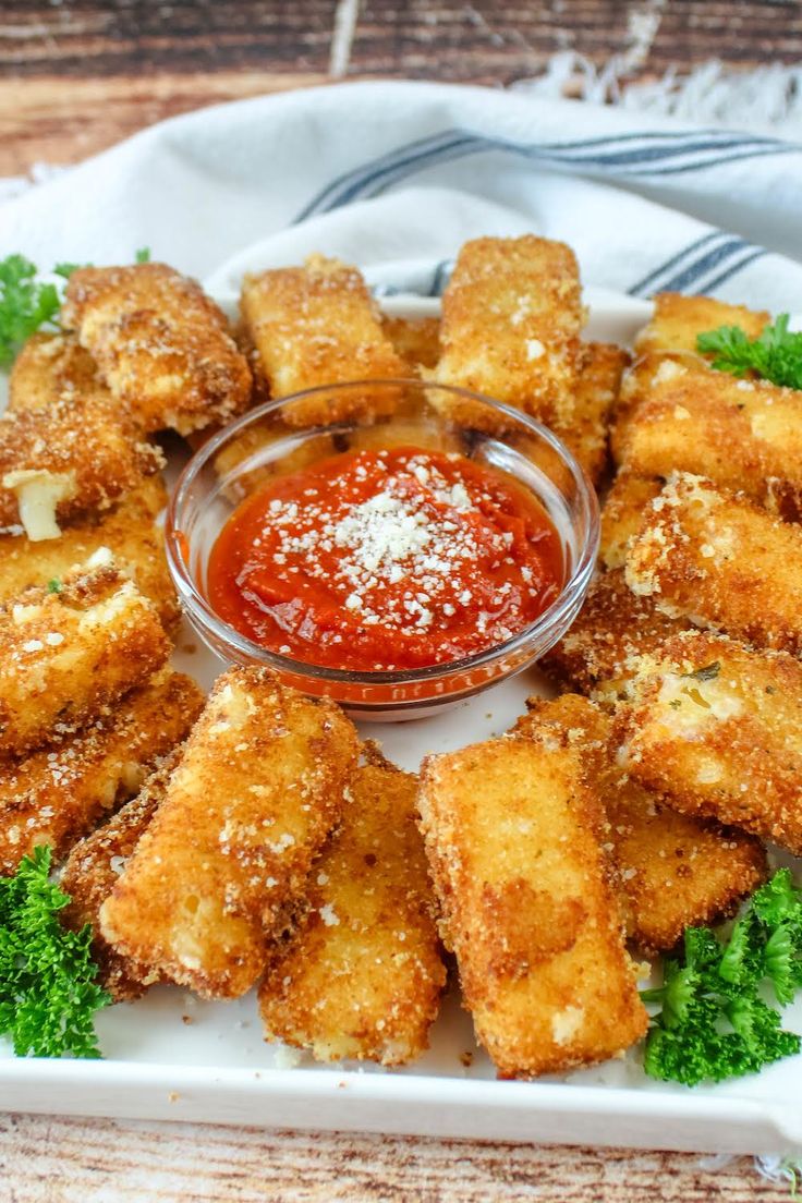 some fried food on a plate with ketchup and parmesan cheese sticks