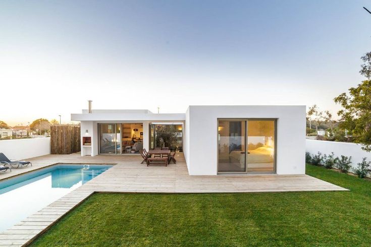 a house with a swimming pool in the middle of it's lawn and patio area