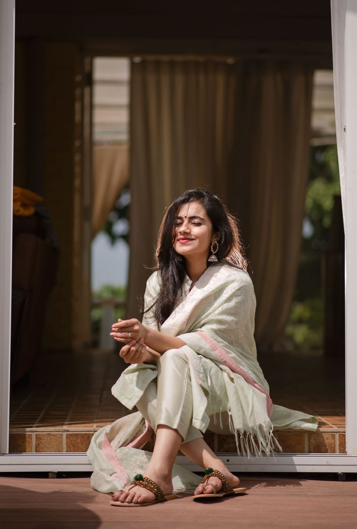 a woman sitting on the ground in front of a door with her hands folded out