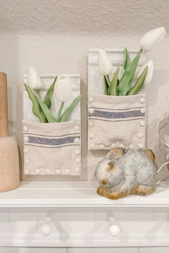 two white flowers are sitting in small baskets on a mantle