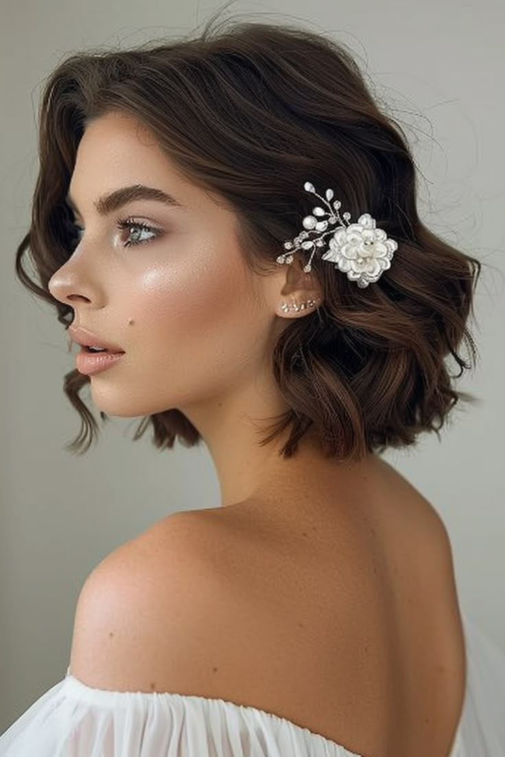 a woman with short hair wearing a white dress and flower clip in her hair, looking off to the side