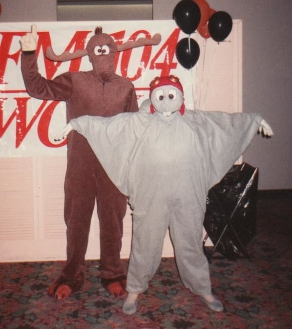 two people dressed up in costumes standing next to each other with balloons on the wall behind them