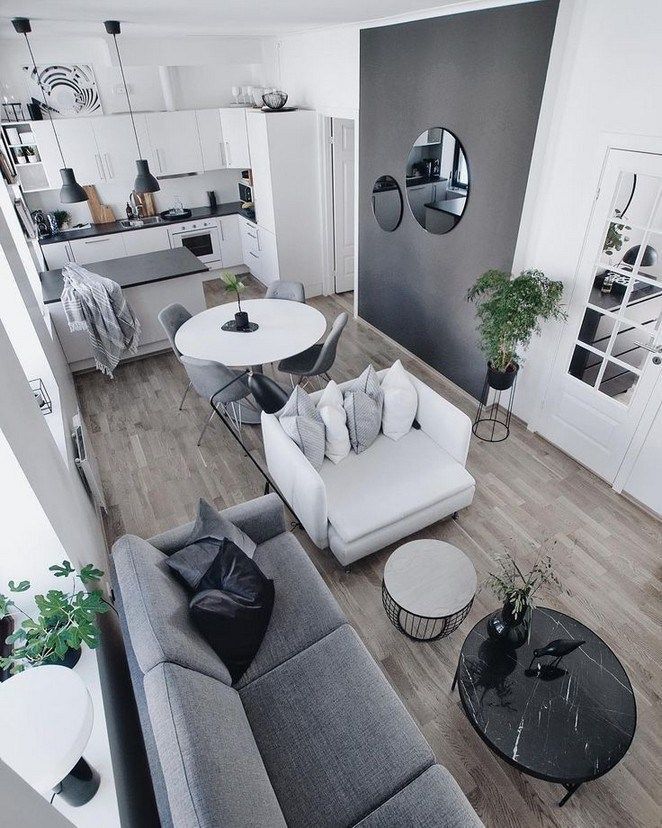 a living room filled with white furniture and lots of mirrors on the wall above it