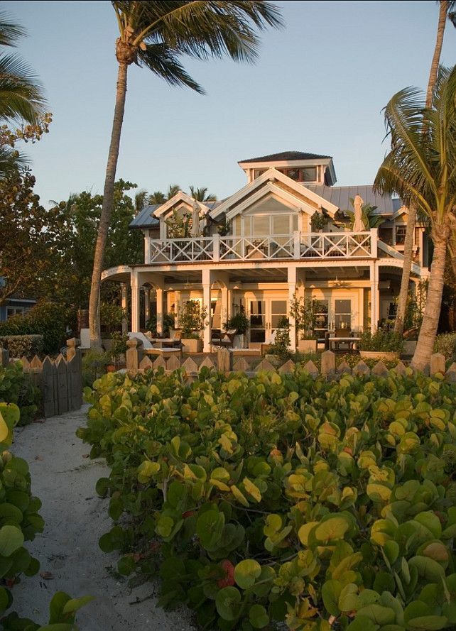 a large house sitting on top of a lush green field next to palm trees and bushes