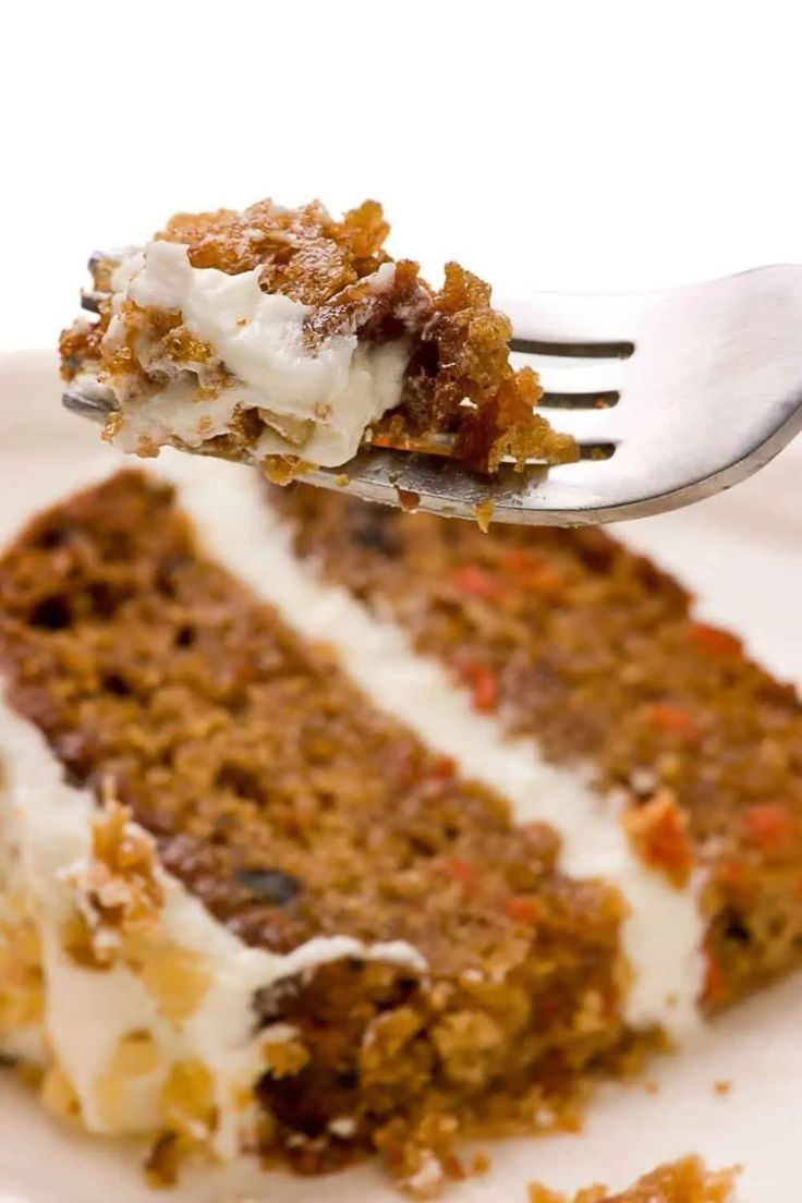 a piece of carrot cake on a white plate with a fork sticking out of it