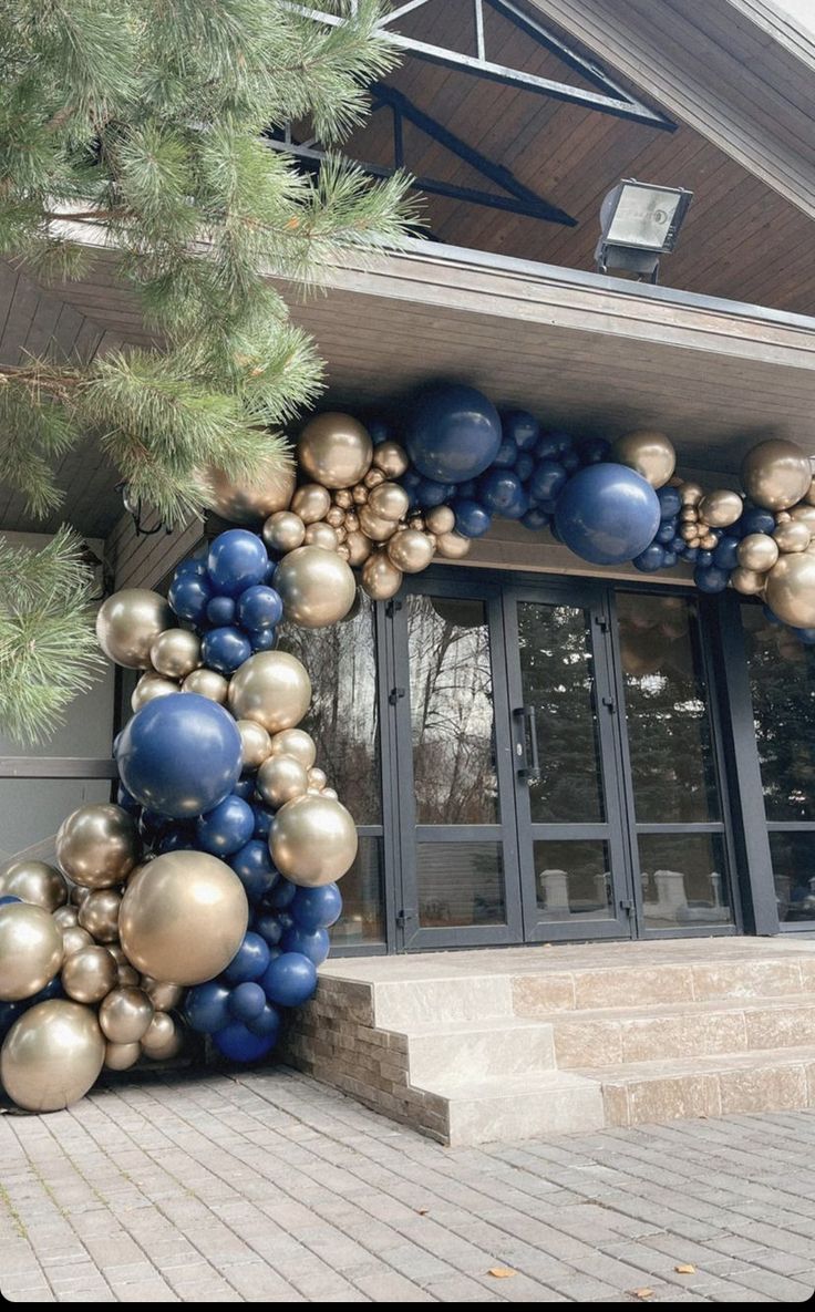 a bunch of balloons that are in front of a building with stairs and trees on the side