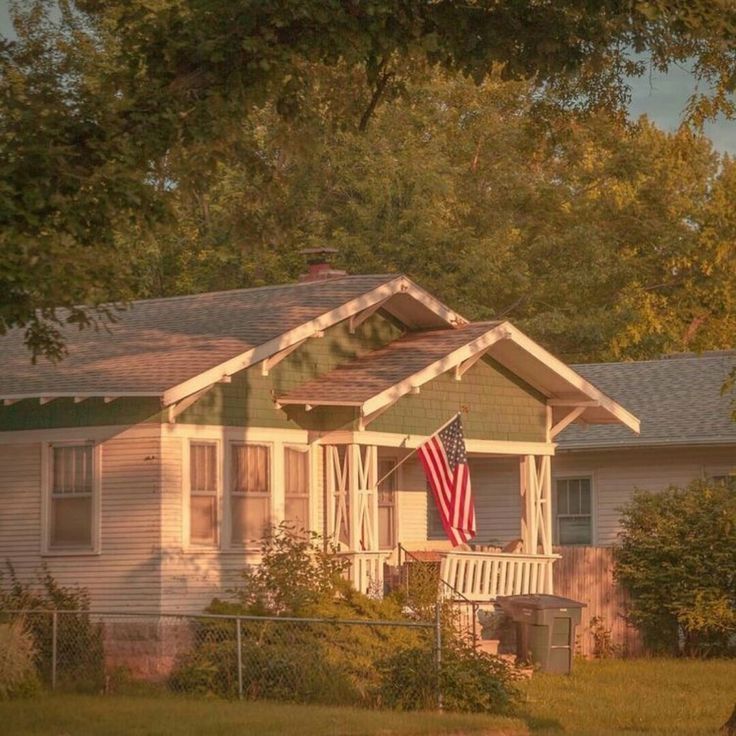 a house with an american flag on the front porch and trees in the back yard