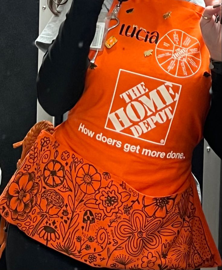 a woman wearing an orange shirt with the words, the home depot on it's back