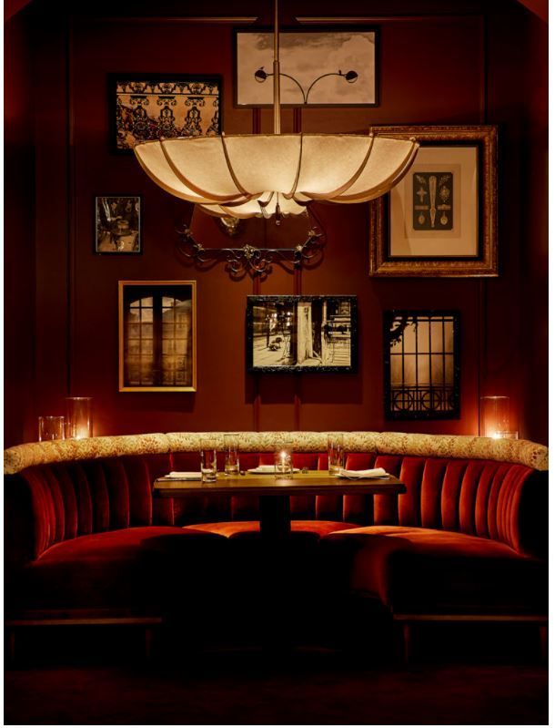 a dimly lit dining room with red velvet booths and chandelier