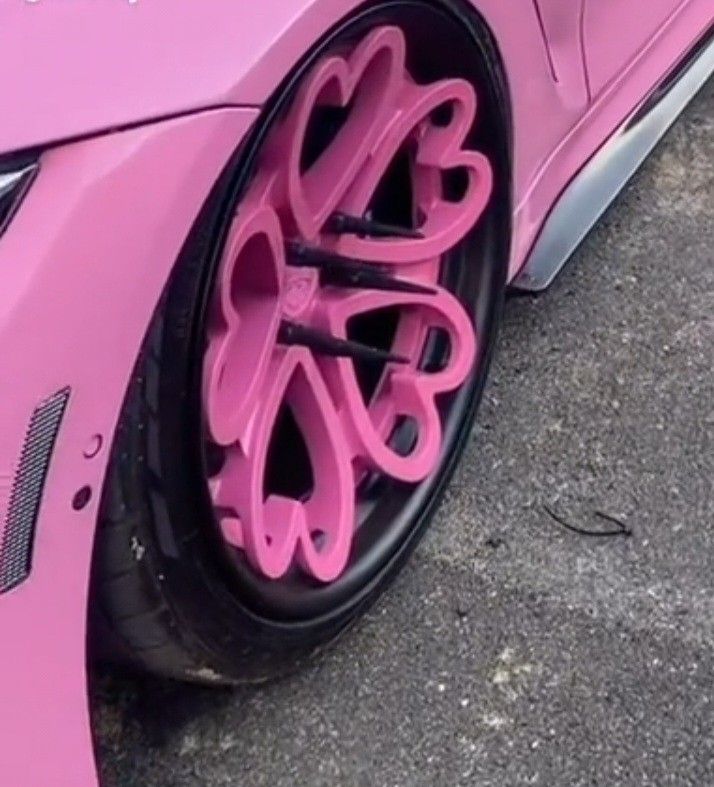 a pink sports car is parked on the side of the road with hearts painted on it