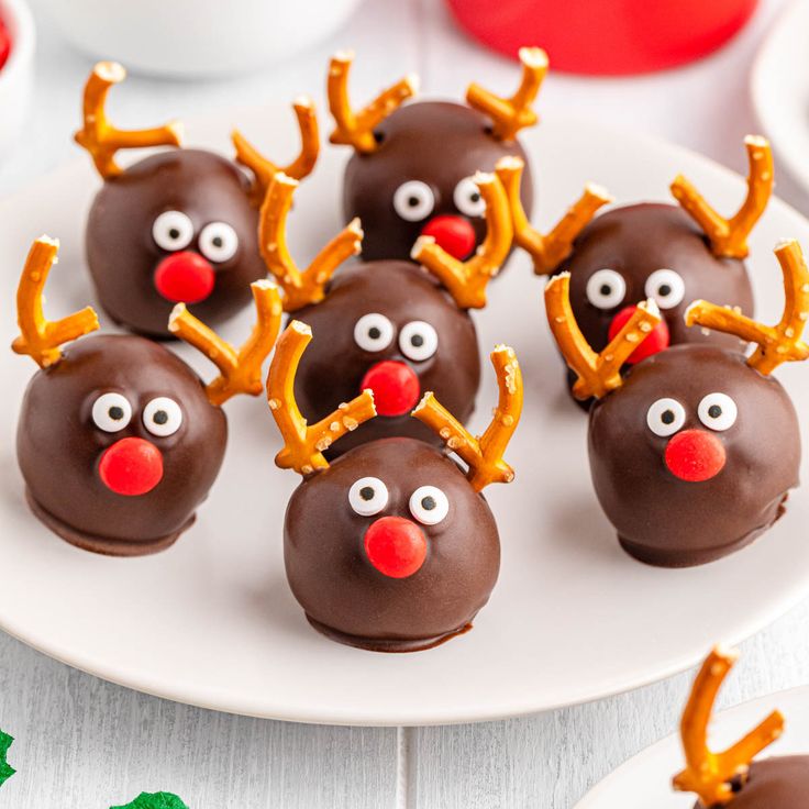 chocolate covered pretzels decorated with reindeer noses and antlers on a white plate