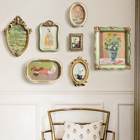 a chair sitting in front of a wall with many framed pictures on it's walls