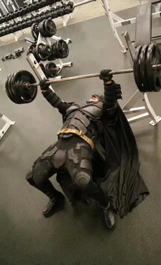 a batman statue holding a barbell in his hands