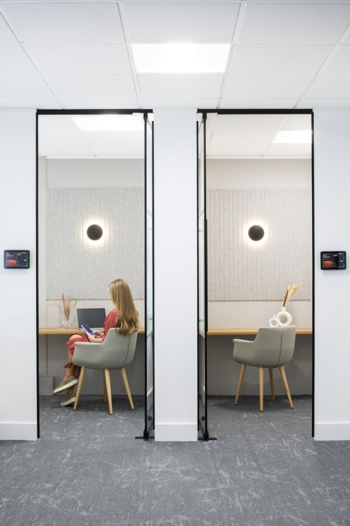 a woman is sitting at a desk in an office with two mirrors on the wall