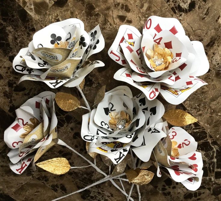 four playing cards are placed on top of each other with gold leafy stems in the middle