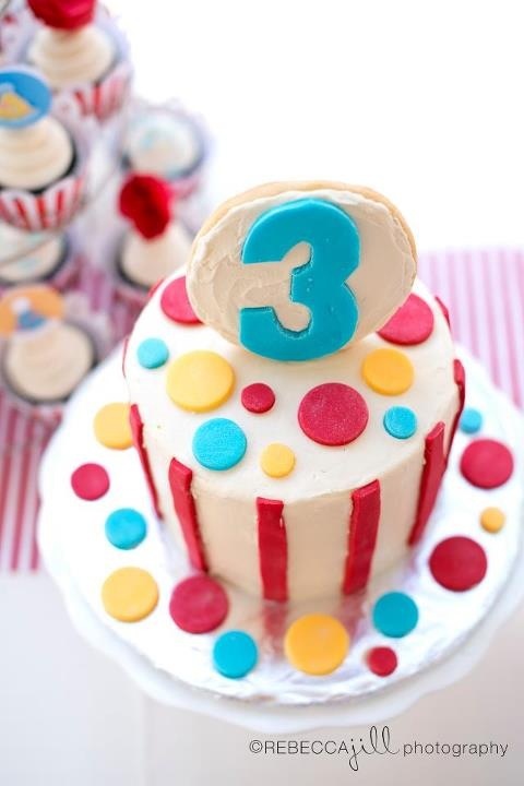 a birthday cake with the number three on it and cupcakes in the background