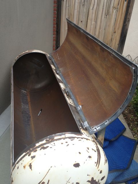 an old metal box sitting on the ground next to a blue towel and a wooden fence