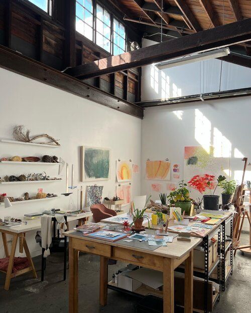 an artist's studio with lots of art work on the walls and desks