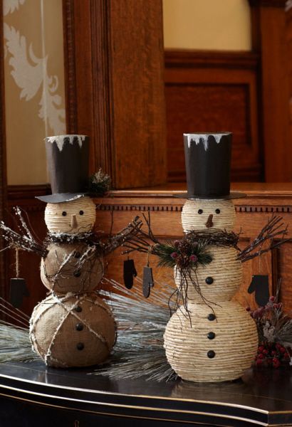 two snowmen sitting on top of a black table in front of a wooden mirror