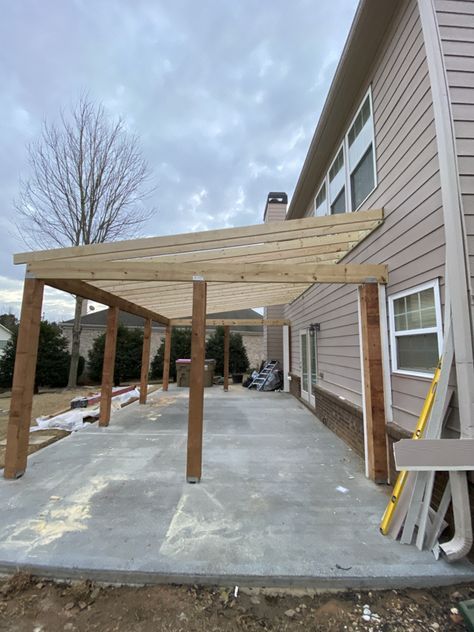 an outdoor covered patio in front of a house with wood posts and siding on the sides