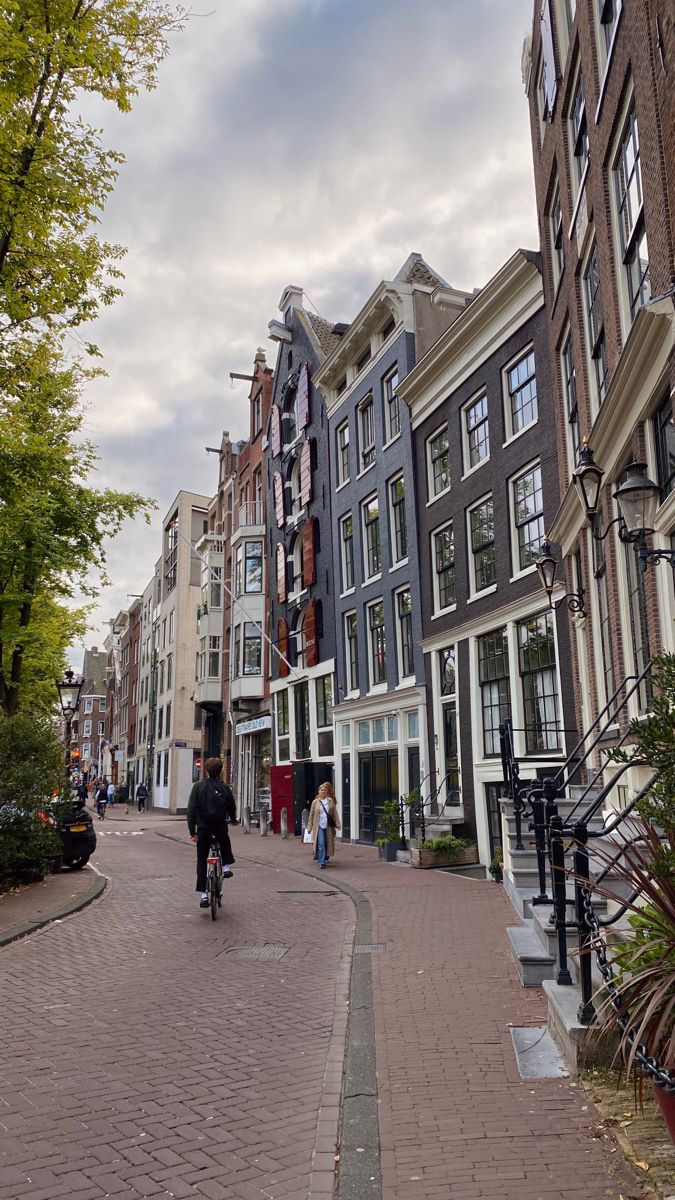 a man riding a bike down a street next to tall buildings on either side of the road