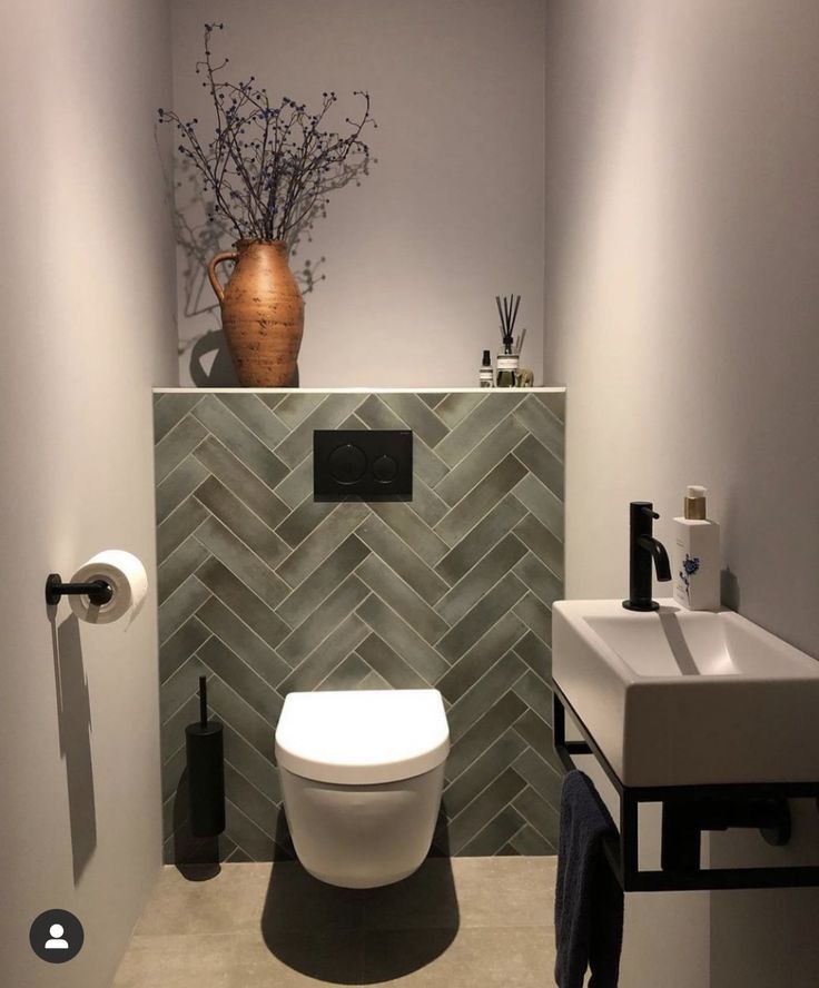 a white toilet sitting in a bathroom next to a sink and towel dispenser