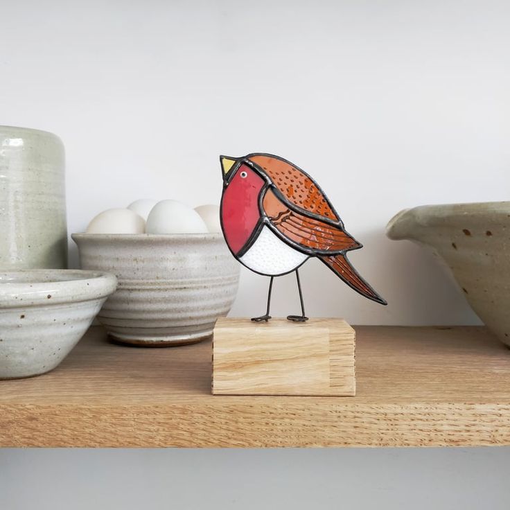 a bird figurine sitting on top of a shelf next to bowls and eggs