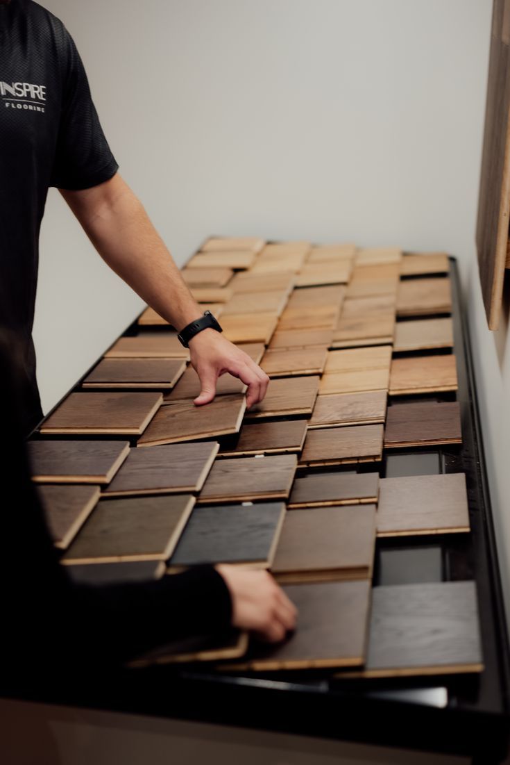 a man standing next to a table covered in different types of wood tiles on it