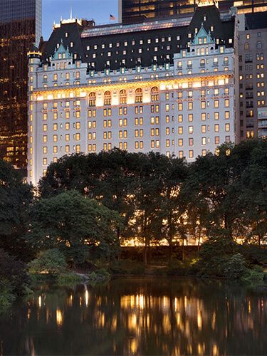 the hotel is lit up at night with its lights on and reflecting in the water