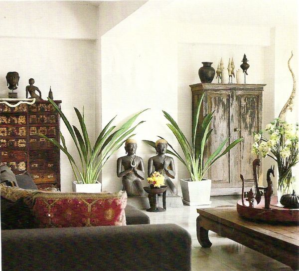 a living room filled with lots of furniture and plants in vases on top of tables