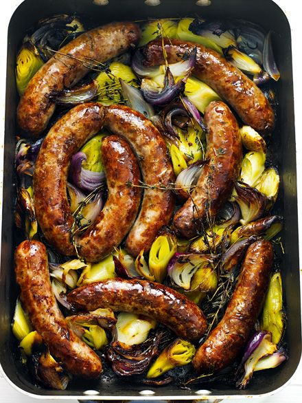 sausages and onions in a roasting pan with herbs