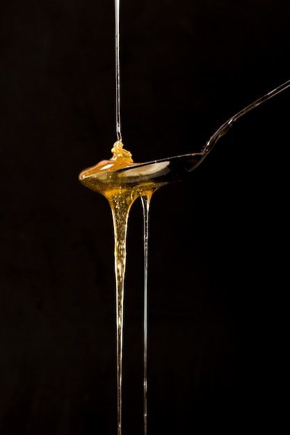 a spoon full of honey dripping from it