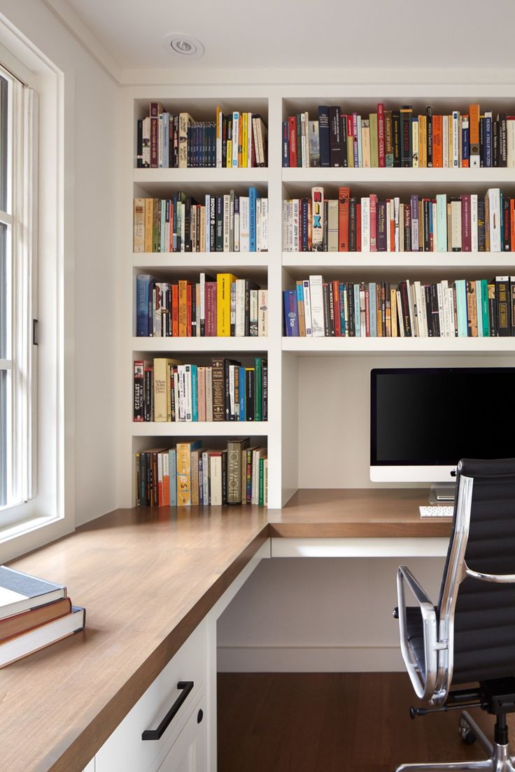 an office desk with a computer and bookshelf in the background, along with a window