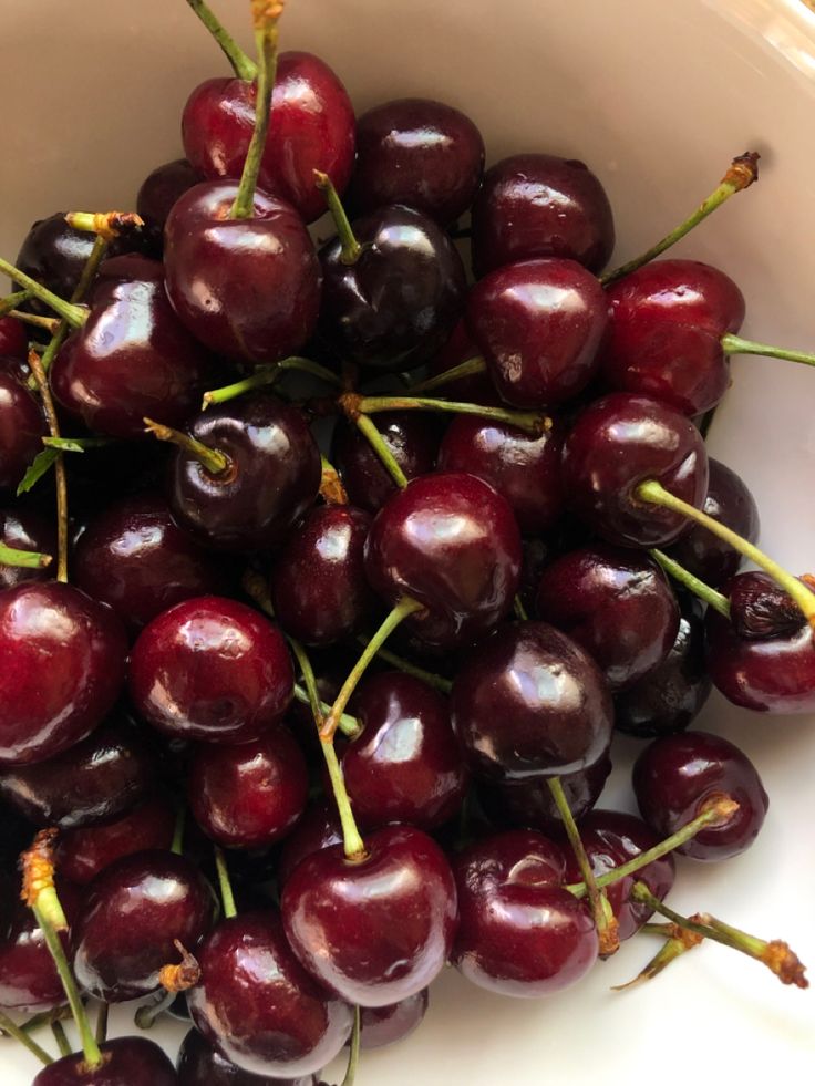 a white bowl filled with cherries on top of a table