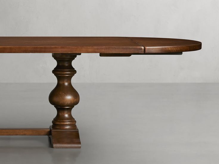 a wooden table sitting on top of a metal floor next to a white wall in an empty room