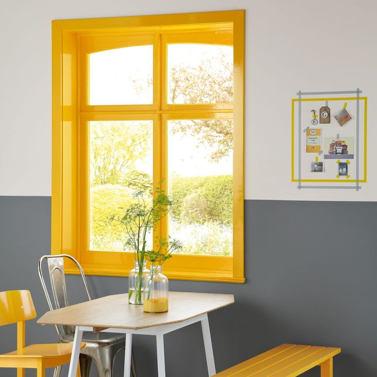 a table and two chairs in front of a window with yellow frames on the wall