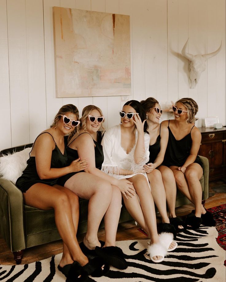 four women sitting on a couch with their legs crossed