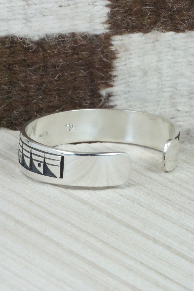 This sterling silver bracelet was made by Hopi silversmith Timothy Mowa. The inside is signed and stamped sterling.Size: 5 5/8" (will fit up to a 6 3/8" wrist)Gap: 3/4"Width: 1/2"Free shipping on all orders! We ship with USPS and always include tracking. All orders ship within a day of payment.Returns are accepted up to 30 days after you receive your order. Just send us a message. Our shop offers cash back or store credit. The item must be returned in new condition. Adjustable Artisan Sterling Silver Bracelet, Etched Sterling Silver Round Bracelets, Artisan Adjustable Bracelets Stamped 925, Sterling Silver Etched Bracelets For Anniversary, Sterling Silver Inlay Bracelets In Silver Color, Symbolic Engraved Sterling Silver Cuff Bracelet, Adjustable Symbolic Sterling Silver Cuff Bracelet, Adjustable Sterling Silver Chain Bracelet For Formal Occasions, Southwestern Sterling Silver Bracelet Stamped 925 As Gift