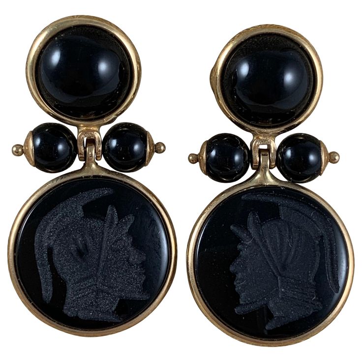 From Italy, a pair of 14-karat gold framed earrings with black onyx cabochons, beads, and carved armorial intaglios. Posted with backs. The upper bezels hold flat back cabochon cut, domed onyx stones, terminating with two pinned and capped onyx beads. The pins hold a swinging, bezeled carved onyx stone, each showing a different Roman helmeted warrior head. Measures: 1 inch Long (25.4 mm) x .75 inch Wide (19.05 mm) .50 inches from front to end of post. Intaglios: .50 inches diameter (12.7 mm) Top Traditional Clothing Around The World, Dragon Food, Regulus Black, Jeweled Earrings, Cabochons Stones, Onyx Bead, Onyx Stone, Jewelry Tools, Cornice