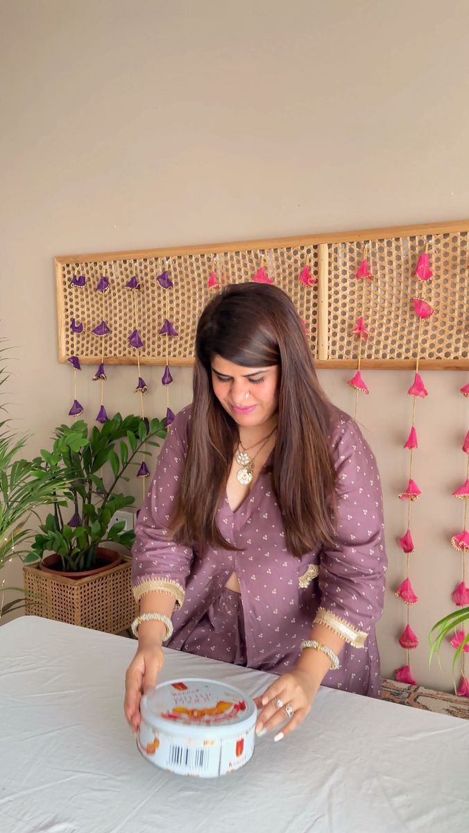 a woman sitting at a table with a bowl of food in front of her and flowers on the wall behind her