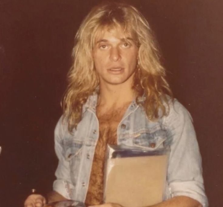 a man with long hair holding a binder