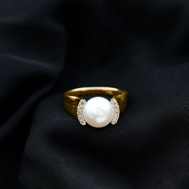 a pearl and diamond ring sitting on top of a black cloth