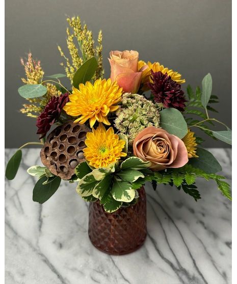 a vase filled with lots of flowers on top of a marble countertop next to a wall