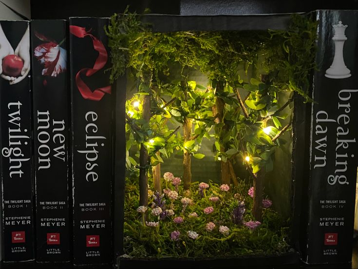 three books with plants and lights on them in front of a black box that says twilight grove