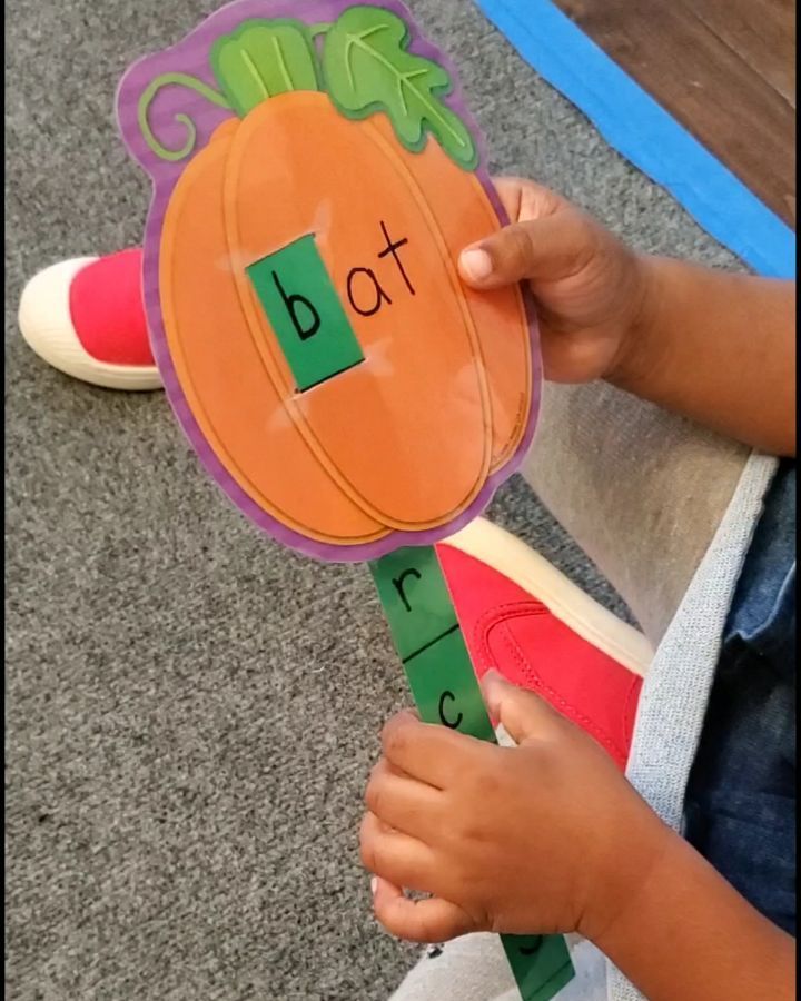 a child holding a carrot shaped toy with the word dot on it's side