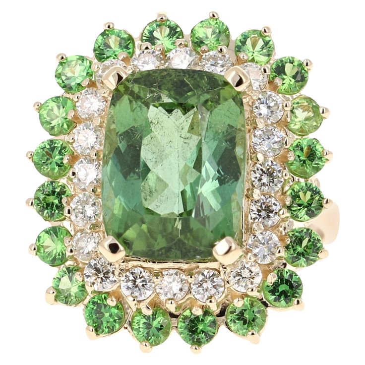 A unique beauty that is sure to be a rare and gorgeous design! This stunner has a gorgeous Rectangular/Cushion Cut leafy Green Tourmaline that weighs 7.90 Carats. Surrounding the Tourmaline are 20 Round Cut Diamonds that weigh 0.90 Carats with a clarity and color of SI1-H. Further its embellished with 20 Tsavorites that weigh 1.69 Carats with a clarity and color of SI1-H. The total carat weight of the ring is 10.49 Carats. The measurements of the rectangular cushion cut tourmaline are 9 mm x 14 mm. The ring is made in 14 Karat Yellow Gold and weighs approximately 8.2 grams. It is a size 7 and can be re-sized at no additional charge. Chrome Tourmaline, Yellow Gold Cocktail Ring, Sapphire Cocktail Ring, Expensive Rings, Rectangular Cushion, Vintage Cocktail Ring, Vintage Jewelry Art, Contemporary Ring, Gold Cocktail Ring