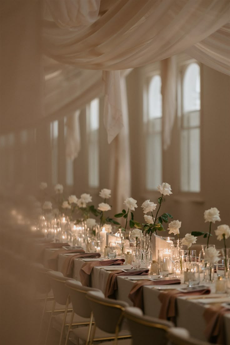 a long table with candles and flowers in vases on top of each table is set for a formal function